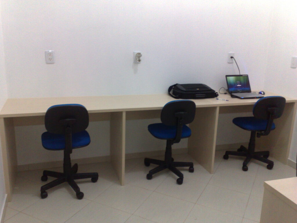 Primeiro escritório da Movtech Systems com três cadeiras azuis e um notebook em uma das mesas.